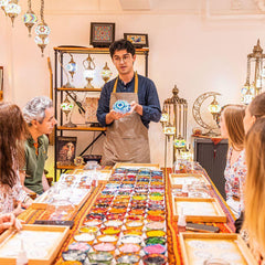 Instructor demonstrating mosaic art in private workshop with colorful tiles and decorative lamps