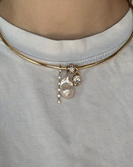 The Demi Tennis Charm choker necklace by Mod + Jo features 14k gold plating and three distinctive pendants—a row of small CZ charms, a large irregular pearl, and a small round crystal—styled here over a white t-shirt.