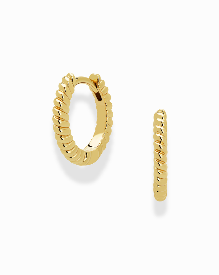 The Mod + Jo Grande Margaux Stacking Hoops are small, tarnish-resistant gold earrings with a twisted rope design. Displayed on a white background, one hoop faces forward and the other sideways. Perfect for pairing with necklace sets.