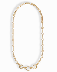 The Jagger Charm Clip Necklace by Mod + Jo features elongated oval links crafted in 14k gold and showcases three larger connected circles at the bottom, elegantly displayed on a white background. This sophisticated necklace seamlessly blends timeless style with contemporary flair.