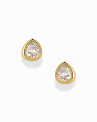 The Joni Bezel Studs by Mod + Jo are gold-plated earrings, each showcasing a clear, pear-shaped cubic zirconia gemstone in a simple bezel setting and displayed on a white background.