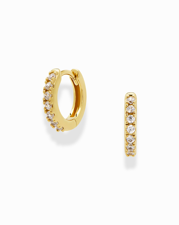 The Mod + Jo Medium Reese Hoops feature 14k gold plating and a row of clear round gemstones along the front, shown on a plain white background.