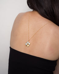 A woman with long dark hair wears the Mod + Jo Perry Four-Leaf Clover Locket Charm necklace, draped down her bare back above a black, strapless top.