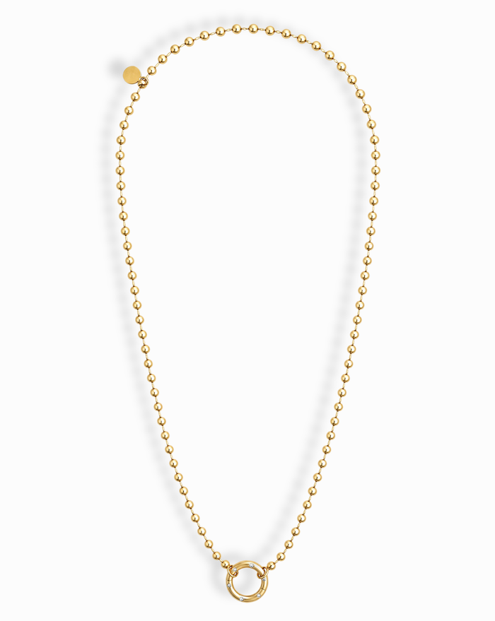 Introducing the Soren Ball Charm Clip Necklace by Mod + Jo: a gold-plated ball chain necklace featuring a circular ring pendant at the center. This 14k gold necklace forms an elegant oval shape, finished with a small round charm attached near the clasp. Photographed on a white background.