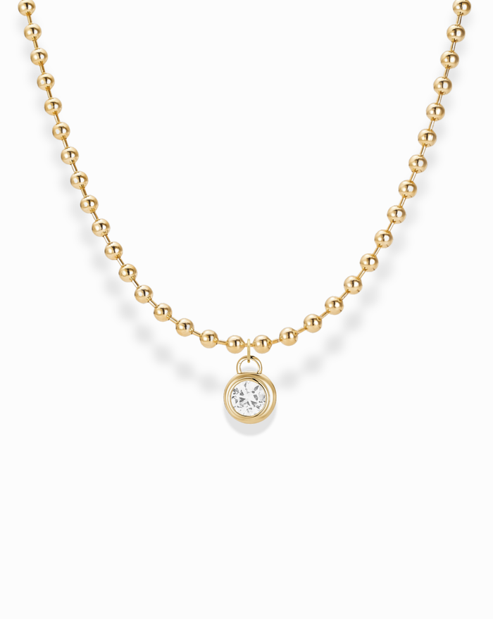 The Soren Bezel Pendant Necklace features a single round, lab-grown white sapphire set in a 14k gold-plated, nickel-free beaded chain, displayed against a white background.