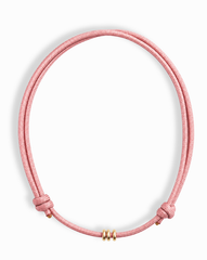 The Tommy Cord Necklace by Mod + Jo features a pink paracord with three gold-plated spacers at the front and adjustable side knots, shown against a white background.