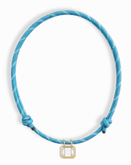 The Mod + Jo Tommy Sapphire Pendant Necklace features a blue cord with two adjustable knots and a gold bezel-set, lab-grown rectangular white sapphire at the center.