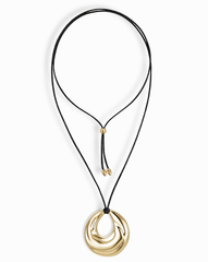 The Mod + Jo Kira Cord Necklace features a black cord with adjustable gold bead fasteners and a bold, shiny abstract gold pendant in an eye-catching circular design.