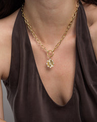 A person wearing a dark, sleeveless top and a chunky gold chain necklace featuring the celestial-inspired Lyra Moon Charm by Mod + Jo.