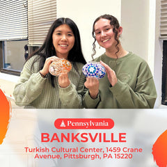 Two women smiling indoors holding colorful mosaic lanterns at Pennsylvania Banksville Turkish Cultural Center