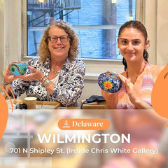 Two women smiling inside Chris White Gallery Wilmington Delaware holding colorful mosaic glass art pieces