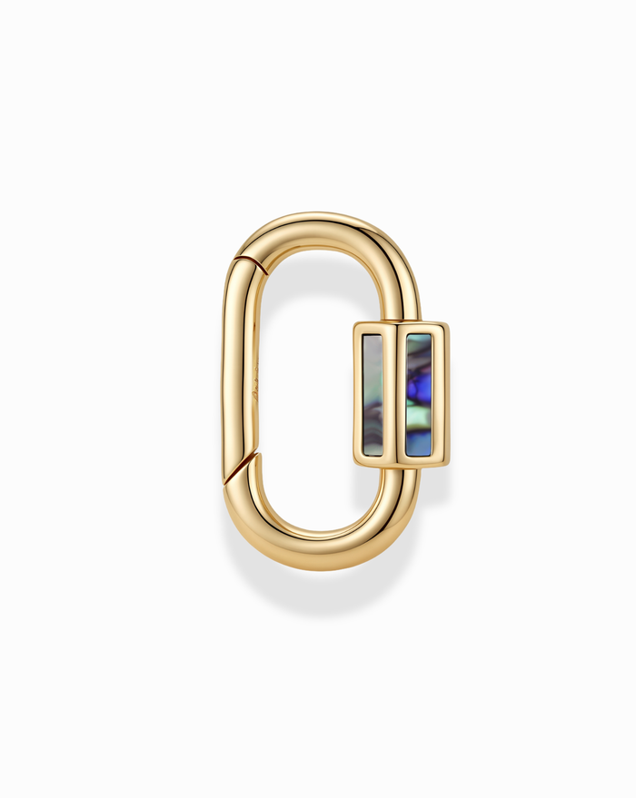 The Nora Lock Carabiner by Mod + Jo features a gold oval-shaped clasp with a rectangular slider, adorned with an iridescent abalone shell inlay and accented by natural semi-precious stones, displayed against a plain white background.