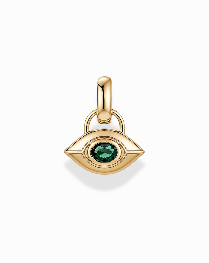 The Mod + Jo Nyx Evil Eye Charm is a gold, eye-shaped pendant featuring a green gemstone at its center, designed with a smooth finish and an attachment loop, shown against a white background.