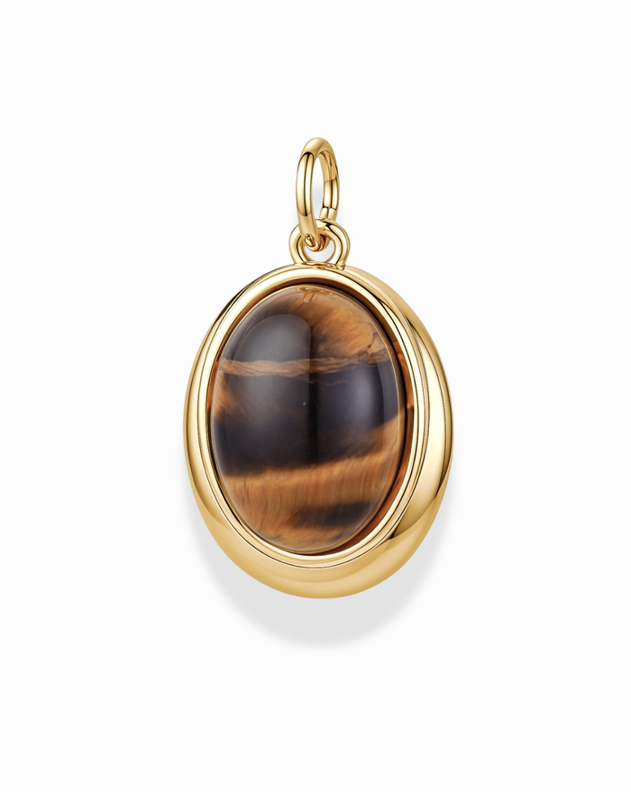 Introducing the Rory Gemstone Charm by Mod + Jo—a stunning gold-plated pendant showcasing an oval Tiger’s Eye gemstone with mesmerizing brown and golden bands. This exquisite piece is set in a polished 14k gold bezel with a convenient loop for your favorite chain, elegantly displayed against a white background. The Rory Gemstone Charm beautifully captures the natural allure of Tiger’s Eye, making it a standout addition to any jewelry collection.