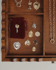 Discover the Rory Gemstone Charm by Mod + Jo—a beautifully crafted wooden jewelry box featuring 14k gold over brass charms in heart, star, and celestial designs. Each charm is thoughtfully arranged in its own compartment alongside unique gemstones such as Dalmatian Jasper, accompanied by a red velvet pouch for an elegant finishing touch.