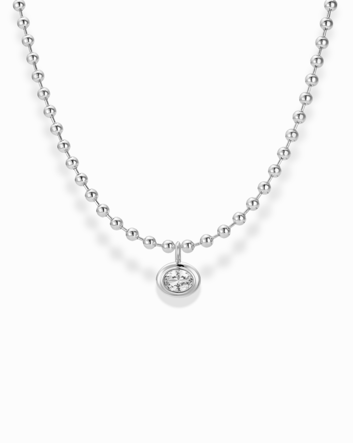 The Soren Bezel Pendant Necklace is a silver beaded necklace with a round pendant featuring a single lab-grown white sapphire, displayed on a white background.