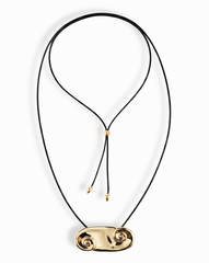 The Suna Spiral Cord Necklace by Mod + Jo features a black cord with an adjustable bolo closure, a sculptural 14k gold pendant with spiral shapes at each end, and two small gold beads on the cord ends.