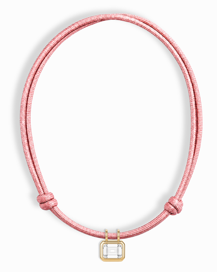The Mod + Jo Tommy Sapphire Pendant Necklace features a pink cord with sliding knots and a rectangular lab-grown white sapphire in a gold bezel setting.