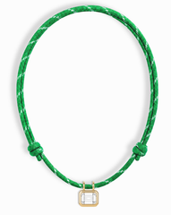 The Mod + Jo Tommy Sapphire Pendant Necklace features a green adjustable paracord with white accents and a rectangular lab-grown white sapphire set in a gold frame at the center.