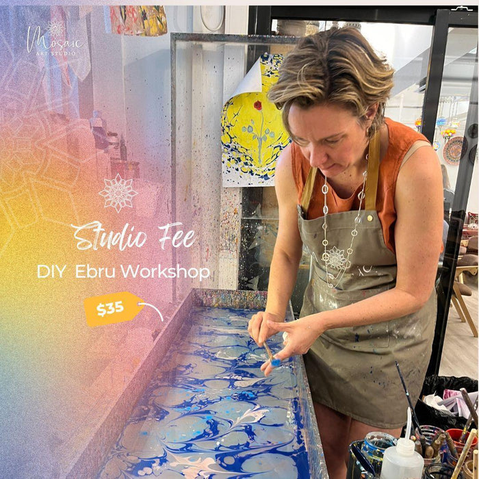 Woman in apron creating blue and white Ebru marbling art in bright art studio for DIY workshop